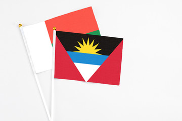 Antigua and Barbuda and Madagascar stick flags on white background. High quality fabric, miniature national flag. Peaceful global concept.White floor for copy space.