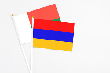 Armenia and Madagascar stick flags on white background. High quality fabric, miniature national flag. Peaceful global concept.White floor for copy space.