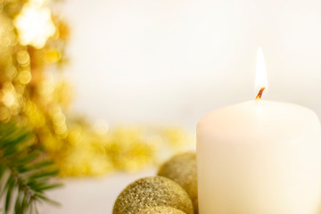burning white candle on the background of the New Year Christmas tree, golden balls. on white...