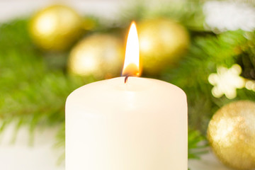 burning white candle on the background of the New Year Christmas tree, golden balls. on white background. festive mood, the sacrament of Christmas.