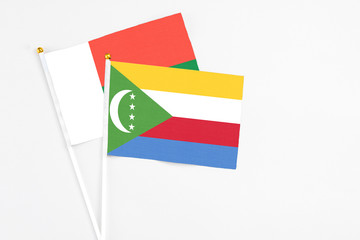 Comoros and Madagascar stick flags on white background. High quality fabric, miniature national flag. Peaceful global concept.White floor for copy space.