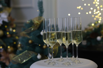Six glasses for champagne and golden Christmas balls against a background of blurred golden lights. Celebrating New Year, Christmas or Birthday with glasses of champagne at party