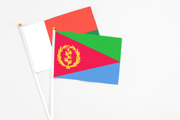Eritrea and Madagascar stick flags on white background. High quality fabric, miniature national flag. Peaceful global concept.White floor for copy space.