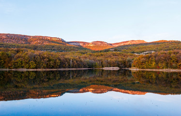 Autumn landscape of the lake at sunset. Lake and autumn forest in the mountains.