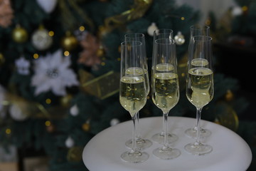 Six glasses for champagne and golden Christmas balls against a background of blurred golden lights. Celebrating New Year, Christmas or Birthday with glasses of champagne at party