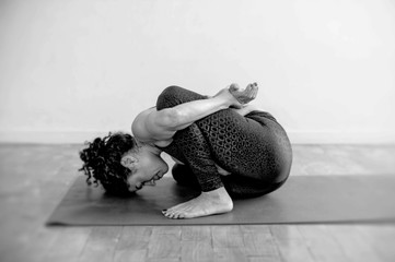 Hispanic yoga woman practicing in studio photographed in black and white. MARICHYASANA B pose