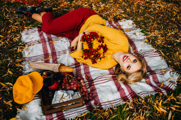 Pretty girl lying on the mat in the park holding a bouquet of chrysanthemums in their hands