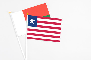 Liberia and Madagascar stick flags on white background. High quality fabric, miniature national flag. Peaceful global concept.White floor for copy space.