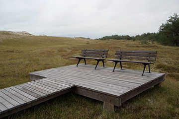 Two isolated benches on a viewpoint with a wooden platform and a wooden plank gangway in front of...