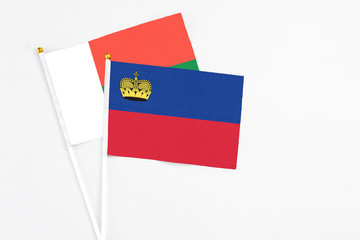 Liechtenstein and Madagascar stick flags on white background. High quality fabric, miniature national flag. Peaceful global concept.White floor for copy space.