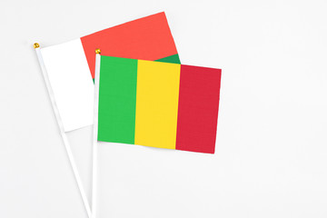 Mali and Madagascar stick flags on white background. High quality fabric, miniature national flag. Peaceful global concept.White floor for copy space.