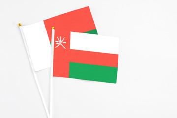 Oman and Madagascar stick flags on white background. High quality fabric, miniature national flag. Peaceful global concept.White floor for copy space.