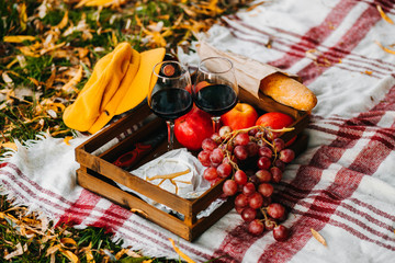 Set for autumn picnic. Basket with grapes, apples, baguette, cheese and wine