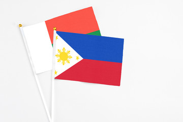 Philippines and Madagascar stick flags on white background. High quality fabric, miniature national flag. Peaceful global concept.White floor for copy space.