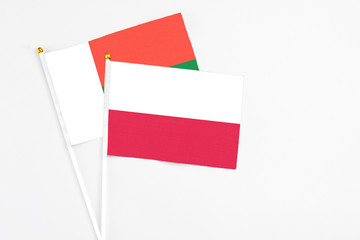 Poland and Madagascar stick flags on white background. High quality fabric, miniature national flag. Peaceful global concept.White floor for copy space.