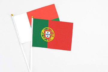 Portugal and Madagascar stick flags on white background. High quality fabric, miniature national flag. Peaceful global concept.White floor for copy space.