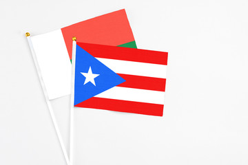 Puerto Rico and Madagascar stick flags on white background. High quality fabric, miniature national flag. Peaceful global concept.White floor for copy space.