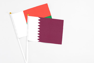 Qatar and Madagascar stick flags on white background. High quality fabric, miniature national flag. Peaceful global concept.White floor for copy space.