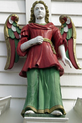 Old wooden and painted angel statue at a white house at the hanseatic wharf at Bryggen in Bergen,...