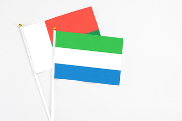Sierra Leone and Madagascar stick flags on white background. High quality fabric, miniature national flag. Peaceful global concept.White floor for copy space.
