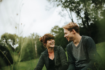 young heterosexual couple sitting in the grass smiling