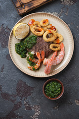 Beige plate with surf and turf meal, view from above on a brown stone background, vertical shot