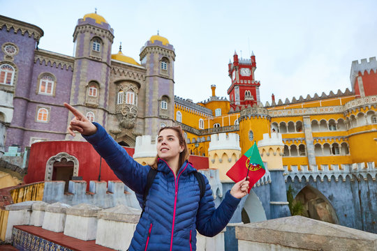Young woman tourist walks in Pena Palace, Sintra holding the flag of Portugal in her hands. Travel and tourism in Europe