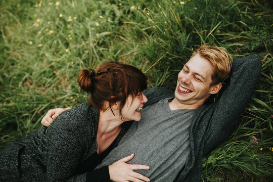young heterosexual couple lying in the grass laughing