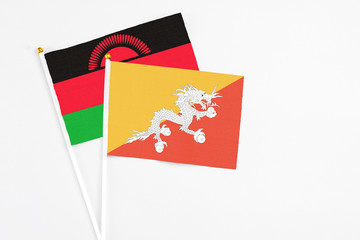 Bhutan and Malawi stick flags on white background. High quality fabric, miniature national flag. Peaceful global concept.White floor for copy space.