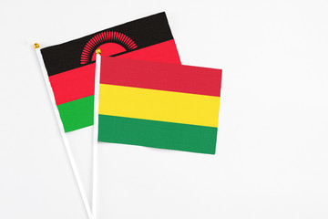 Bolivia and Malawi stick flags on white background. High quality fabric, miniature national flag. Peaceful global concept.White floor for copy space.
