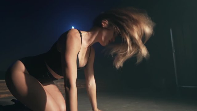 Beautiful woman with long hair in sexy clothes is dancing in dark room. Modern dance, lifestyle, talented girl. Slow motion