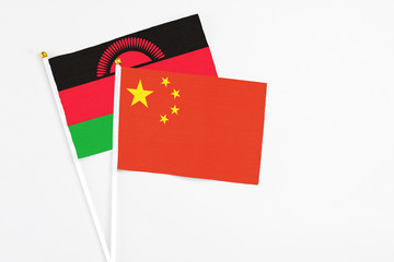 China and Malawi stick flags on white background. High quality fabric, miniature national flag. Peaceful global concept.White floor for copy space.