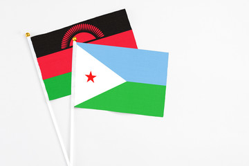 Djibouti and Malawi stick flags on white background. High quality fabric, miniature national flag. Peaceful global concept.White floor for copy space.