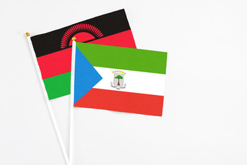 Equatorial Guinea and Malawi stick flags on white background. High quality fabric, miniature national flag. Peaceful global concept.White floor for copy space.
