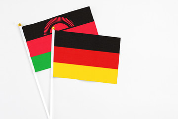 Germany and Malawi stick flags on white background. High quality fabric, miniature national flag. Peaceful global concept.White floor for copy space.
