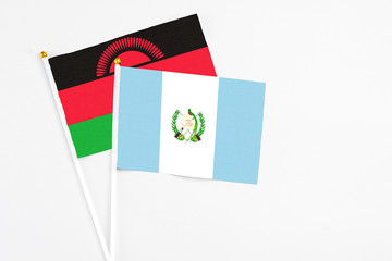 Guatemala and Malawi stick flags on white background. High quality fabric, miniature national flag. Peaceful global concept.White floor for copy space.
