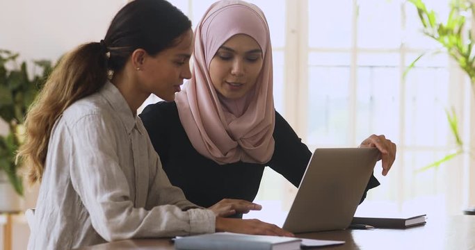 Female muslim manager mentor consulting client teaching intern with laptop