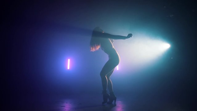 Amazing woman dancing in neon light. Professional dancer sexually moving to the music rhythm. Slow motion.