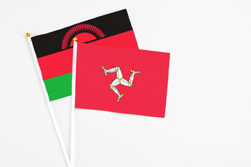 Isle Of Man and Malawi stick flags on white background. High quality fabric, miniature national flag. Peaceful global concept.White floor for copy space.