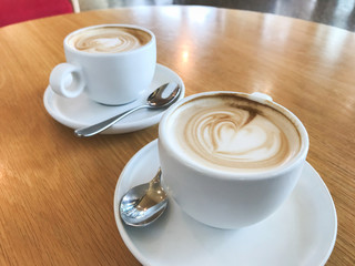Two cups of flat white coffee on wooden table