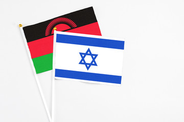 Israel and Malawi stick flags on white background. High quality fabric, miniature national flag. Peaceful global concept.White floor for copy space.