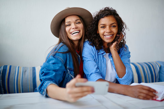 Portrait for cheerful multiracial women posing for common selfie on smartphone during friendly meeting in cafe,hipster girls having fun together laughing making pictures using telephone camera