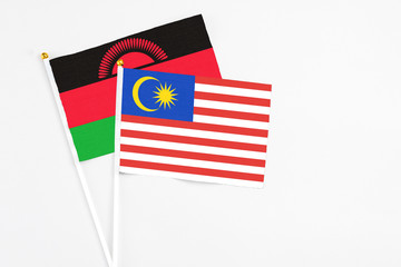 Malaysia and Malawi stick flags on white background. High quality fabric, miniature national flag. Peaceful global concept.White floor for copy space.