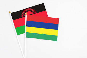 Mauritius and Malawi stick flags on white background. High quality fabric, miniature national flag. Peaceful global concept.White floor for copy space.