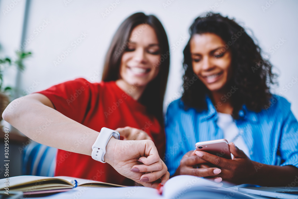 Poster selective focus on female's hand with digital smartwatch synchronizing data with mobile, hipster gir