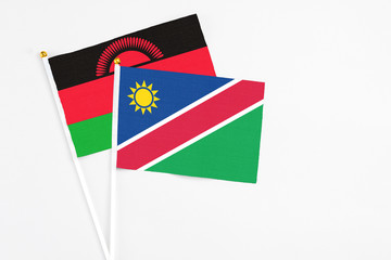 Namibia and Malawi stick flags on white background. High quality fabric, miniature national flag. Peaceful global concept.White floor for copy space.