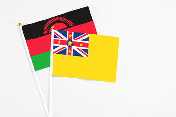 Niue and Malawi stick flags on white background. High quality fabric, miniature national flag. Peaceful global concept.White floor for copy space.