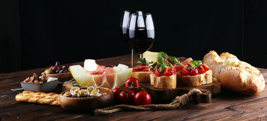 Italian antipasti wine snacks set. Cheese variety, Mediterranean olives, seafood salad, Prosciutto di Parma, tomatoes, anchovy and wine in glasses