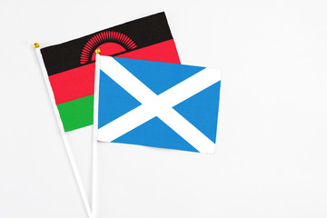 Scotland and Malawi stick flags on white background. High quality fabric, miniature national flag. Peaceful global concept.White floor for copy space.