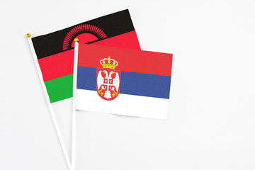 Serbia and Malawi stick flags on white background. High quality fabric, miniature national flag. Peaceful global concept.White floor for copy space.